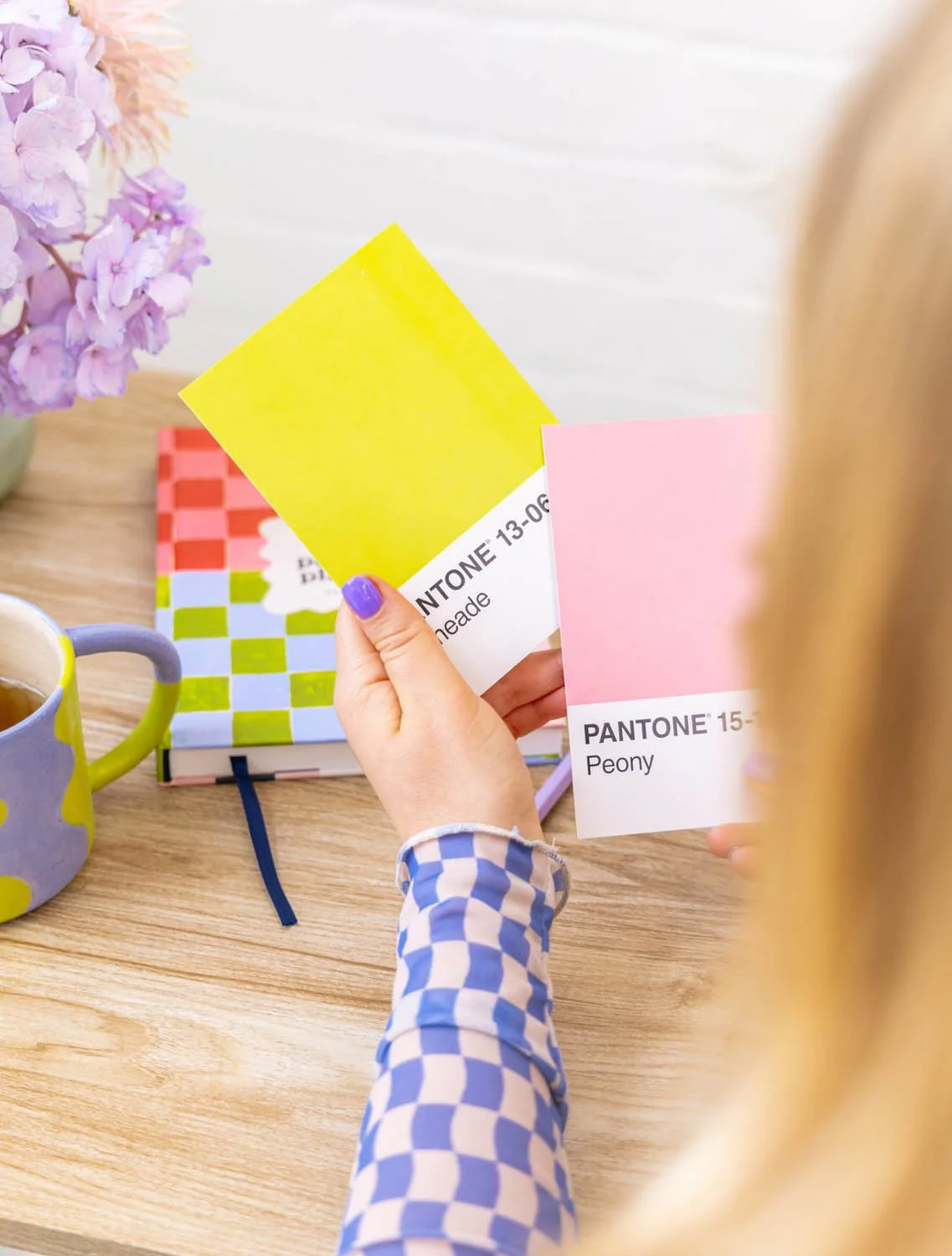 Designer holding yellow and pink Pantone colour swatches