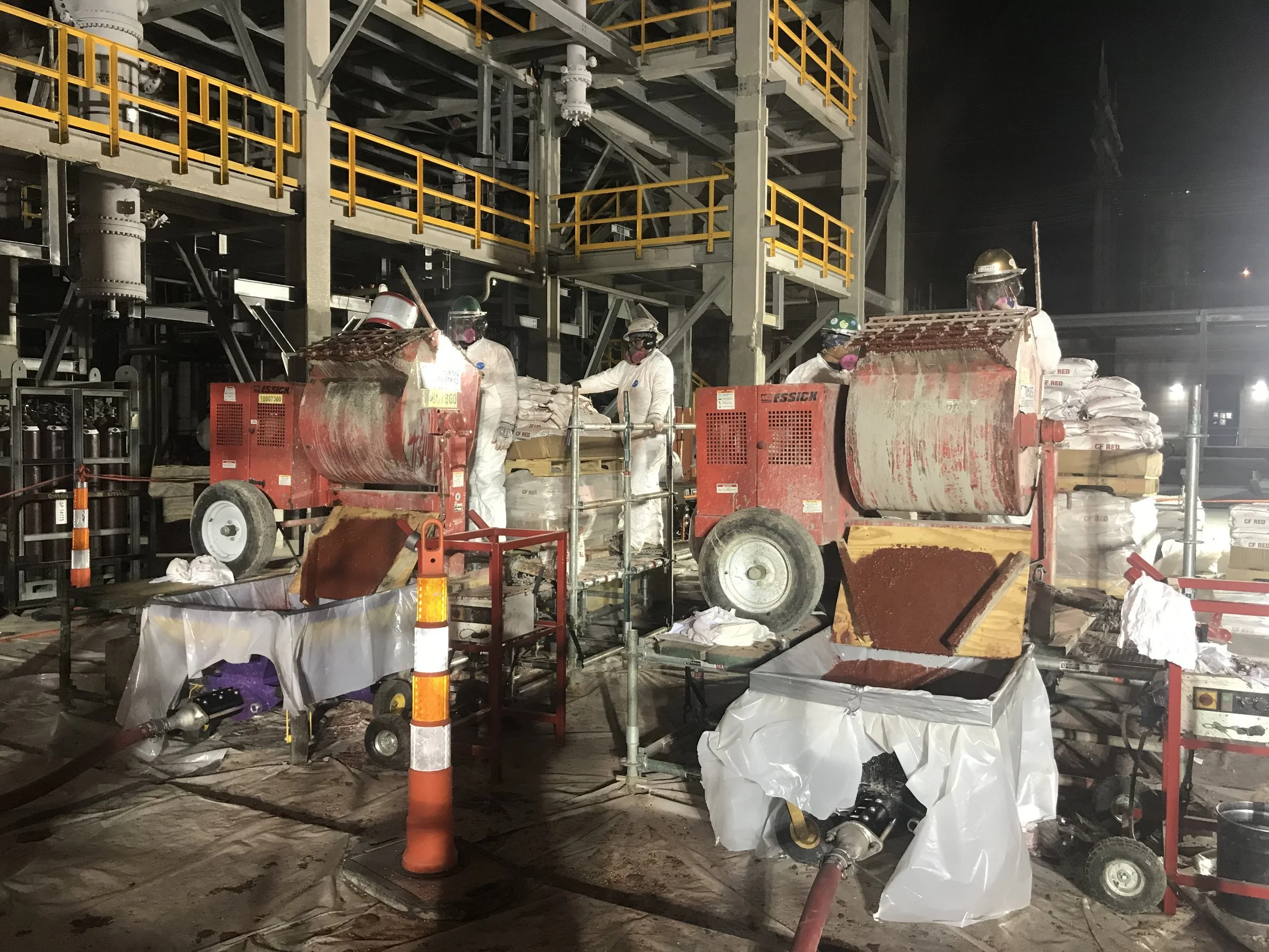 BSA crew pumping epoxy grout on elevated industrial equipment installation at night