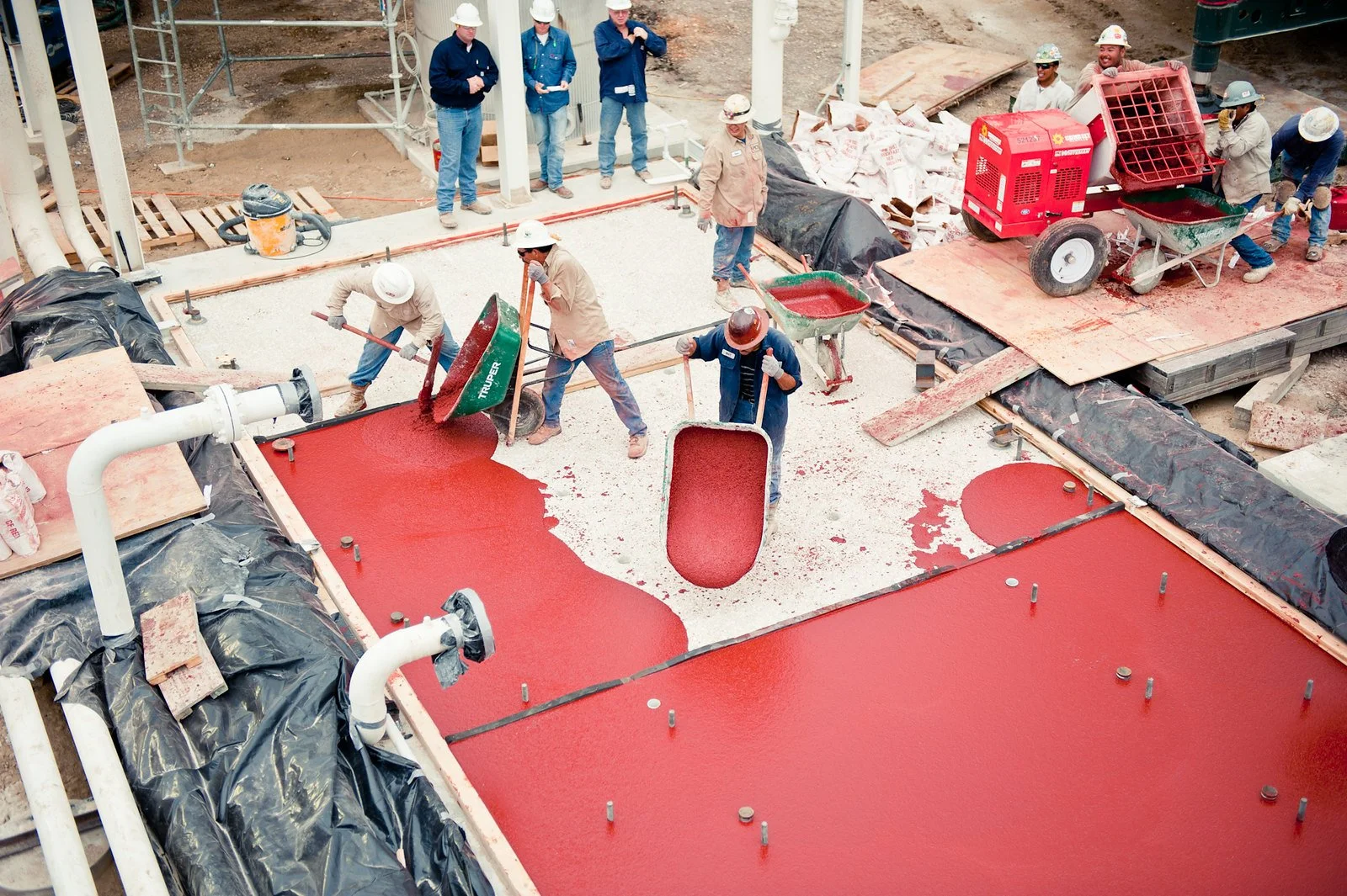 Workers pouring and spreading Chockfast Red epoxy grout on compressor foundation