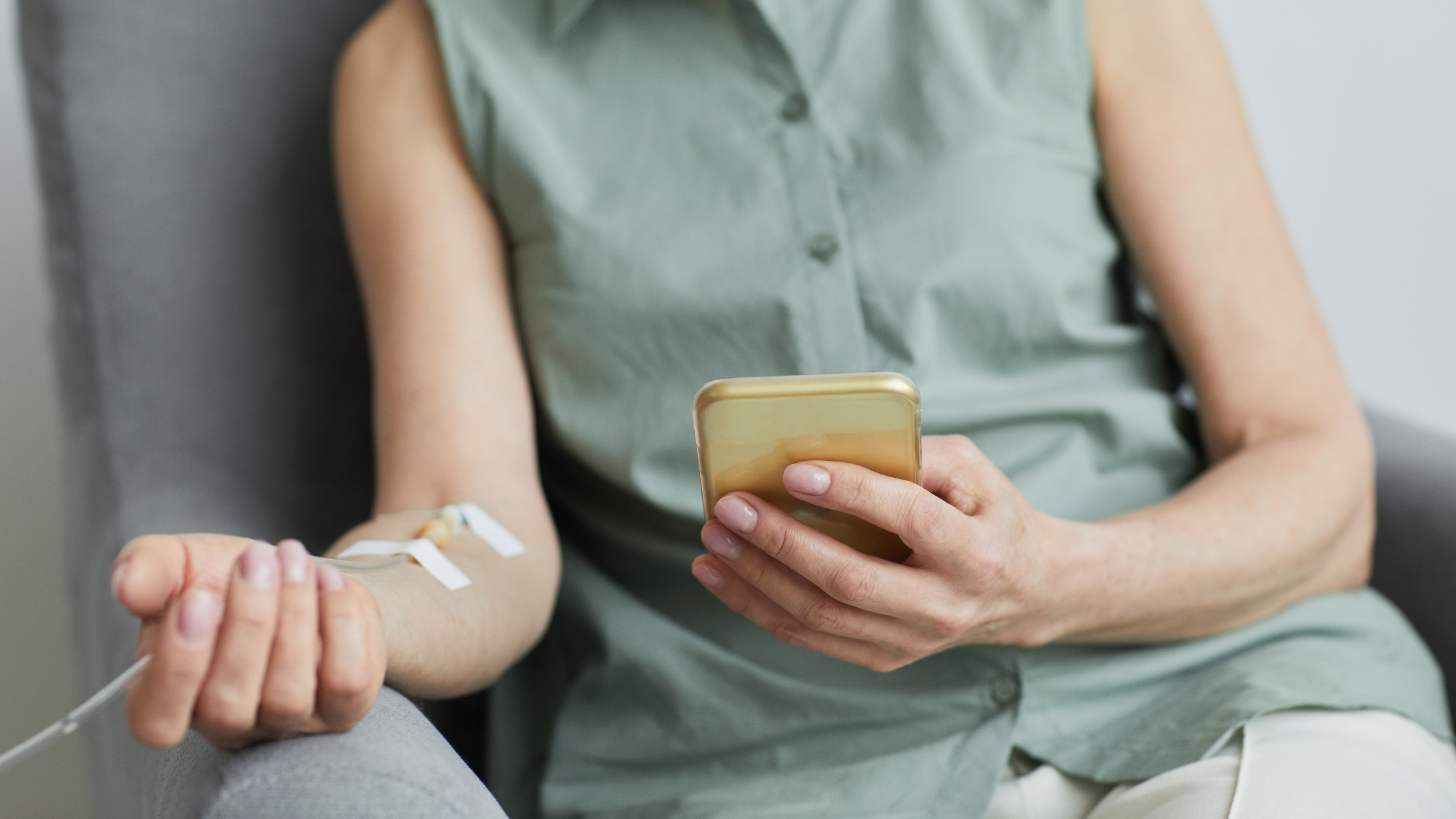 Person getting a wellness IV while sitting on their phone.