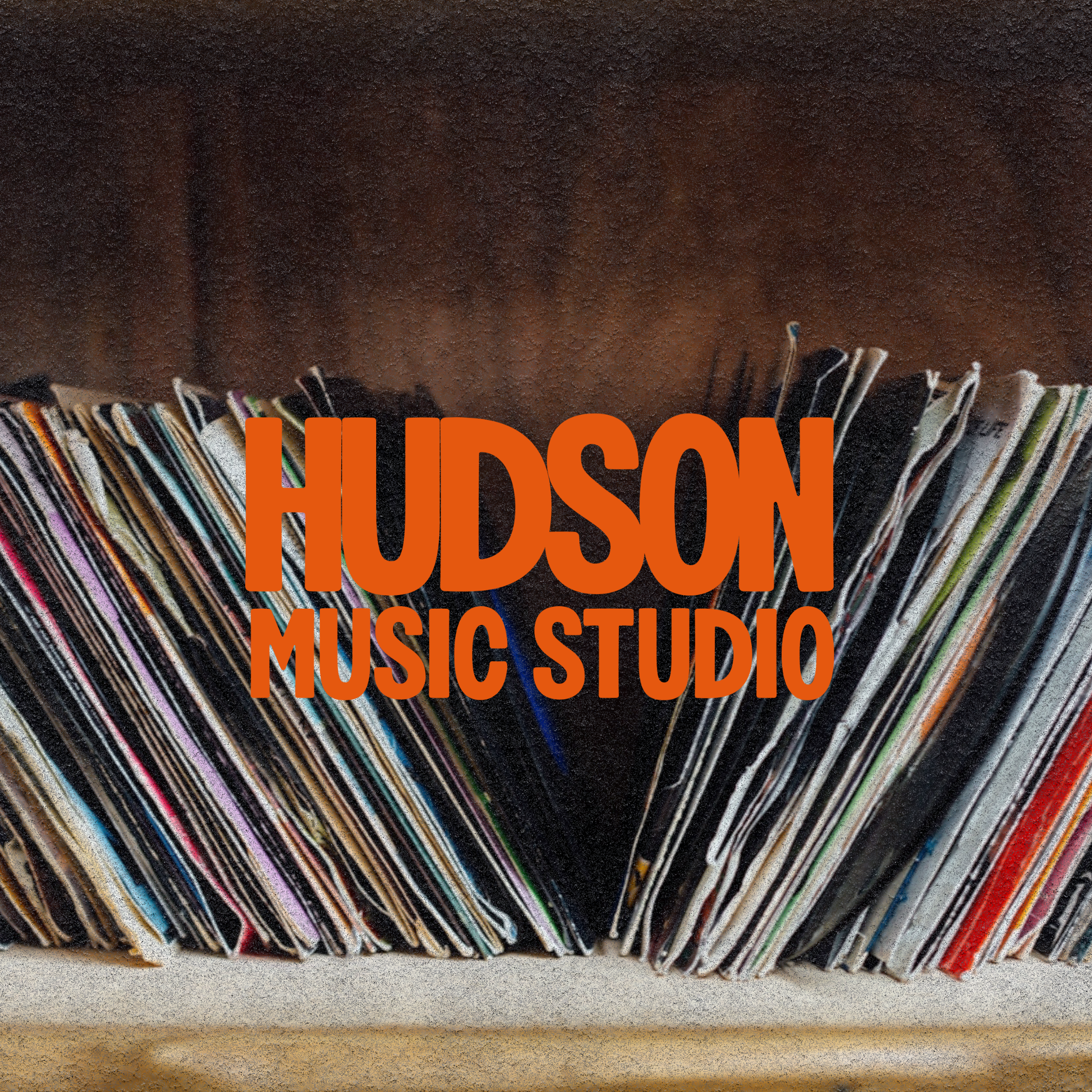 A collection of vinyl records stand upright on a shelf with the text 'Hudson Music Studio' overlayed in large orange letters.