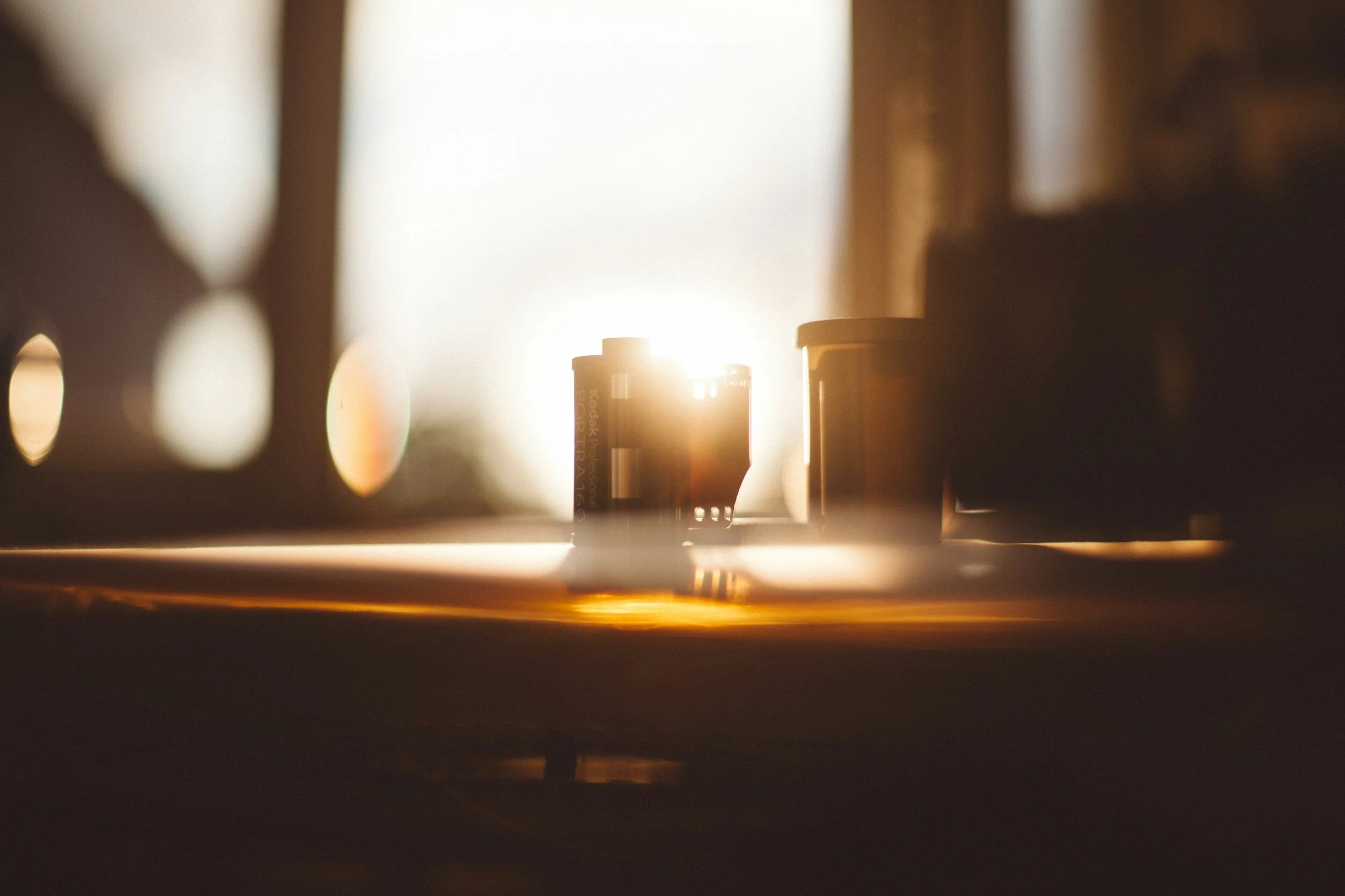 Close-up of camera film canisters placed on a surface with sunlight shining behind them.