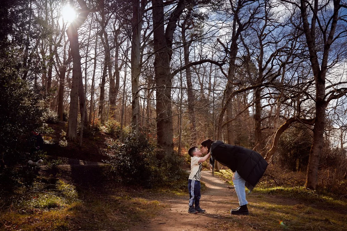 Mother and child kiss on a forest trail in winter.