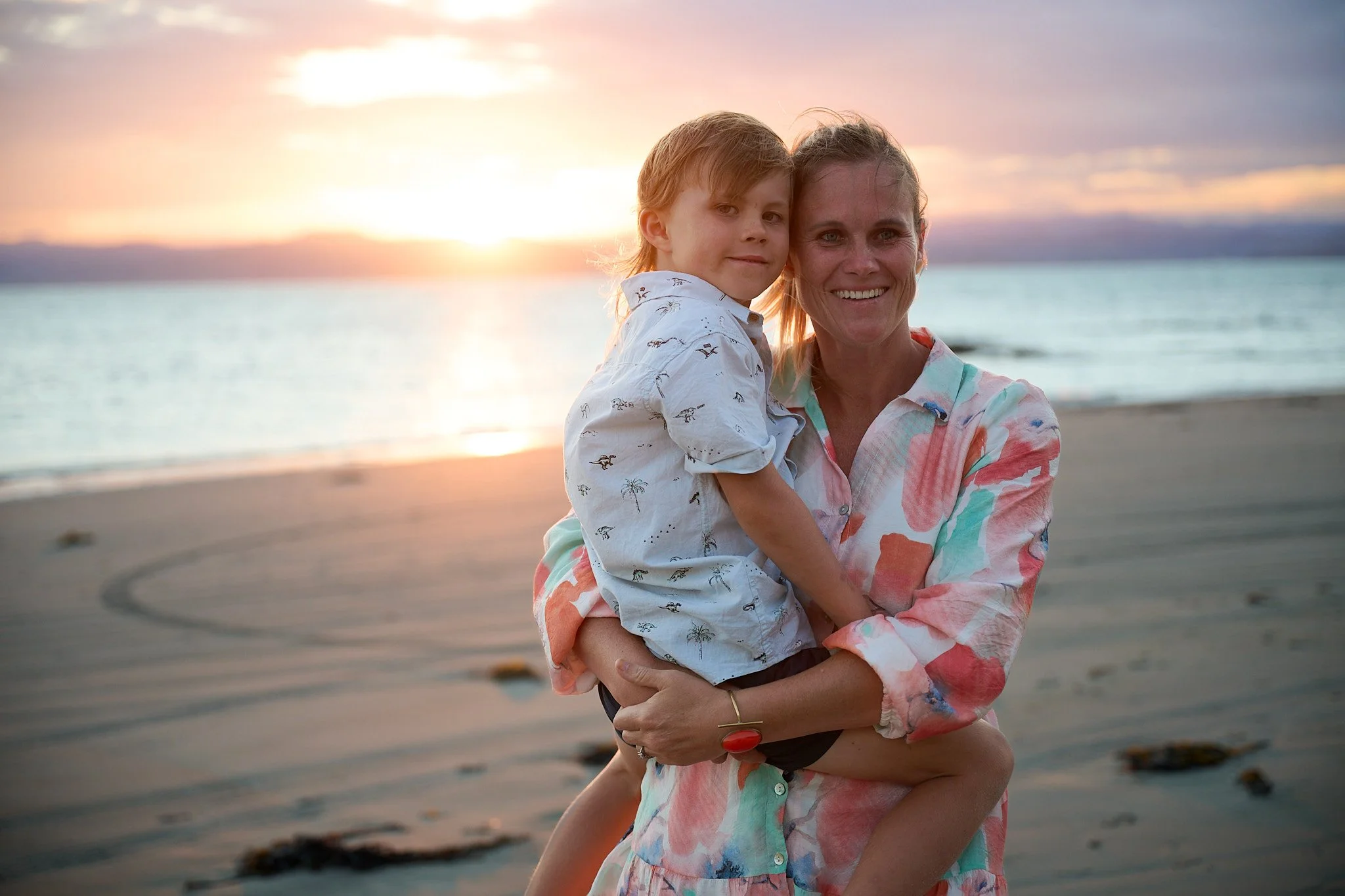 Mother and child on a beach at sunset.