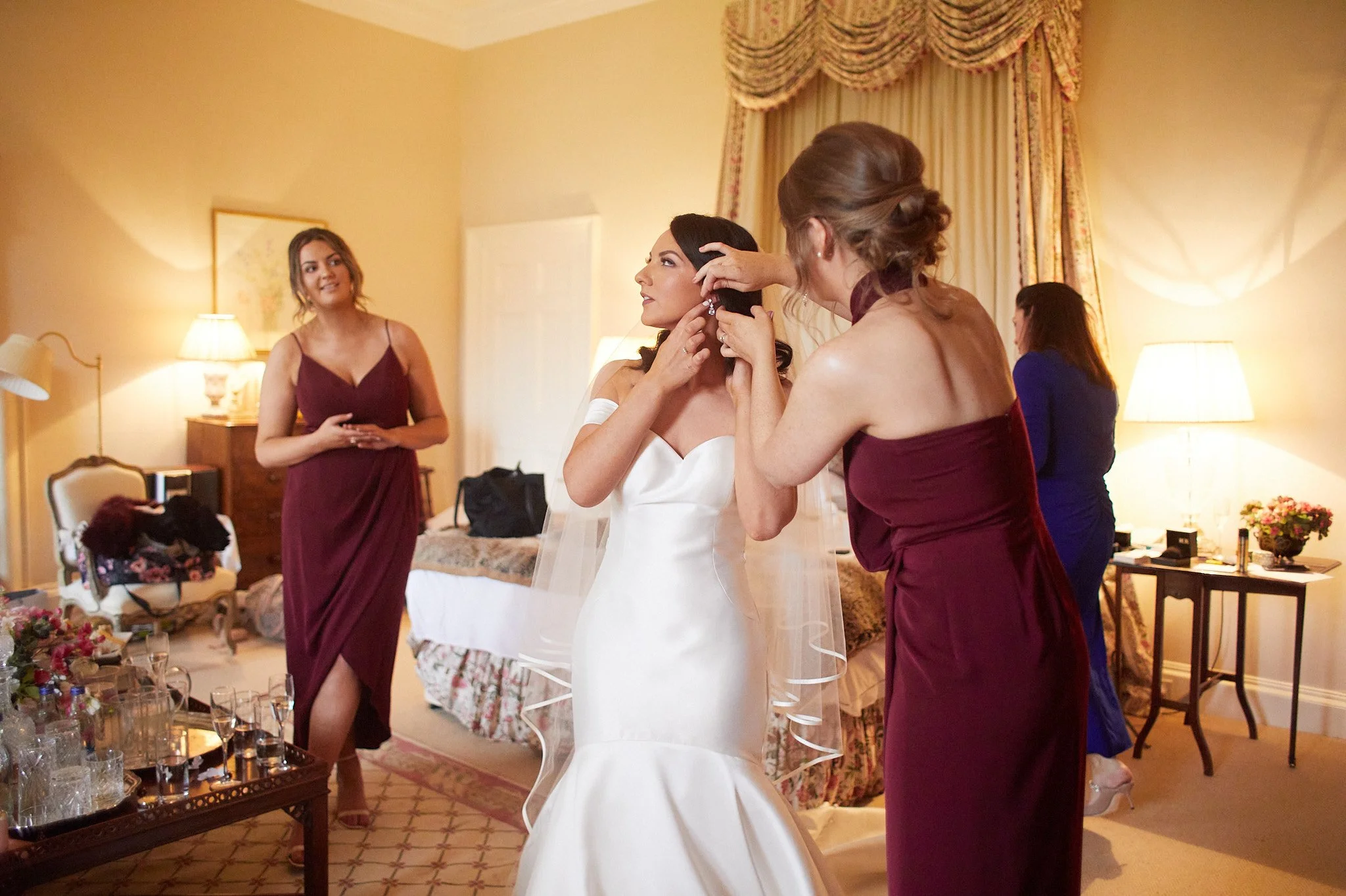 Bride getting ready with bridesmaids helping in a room with elegant decor.
