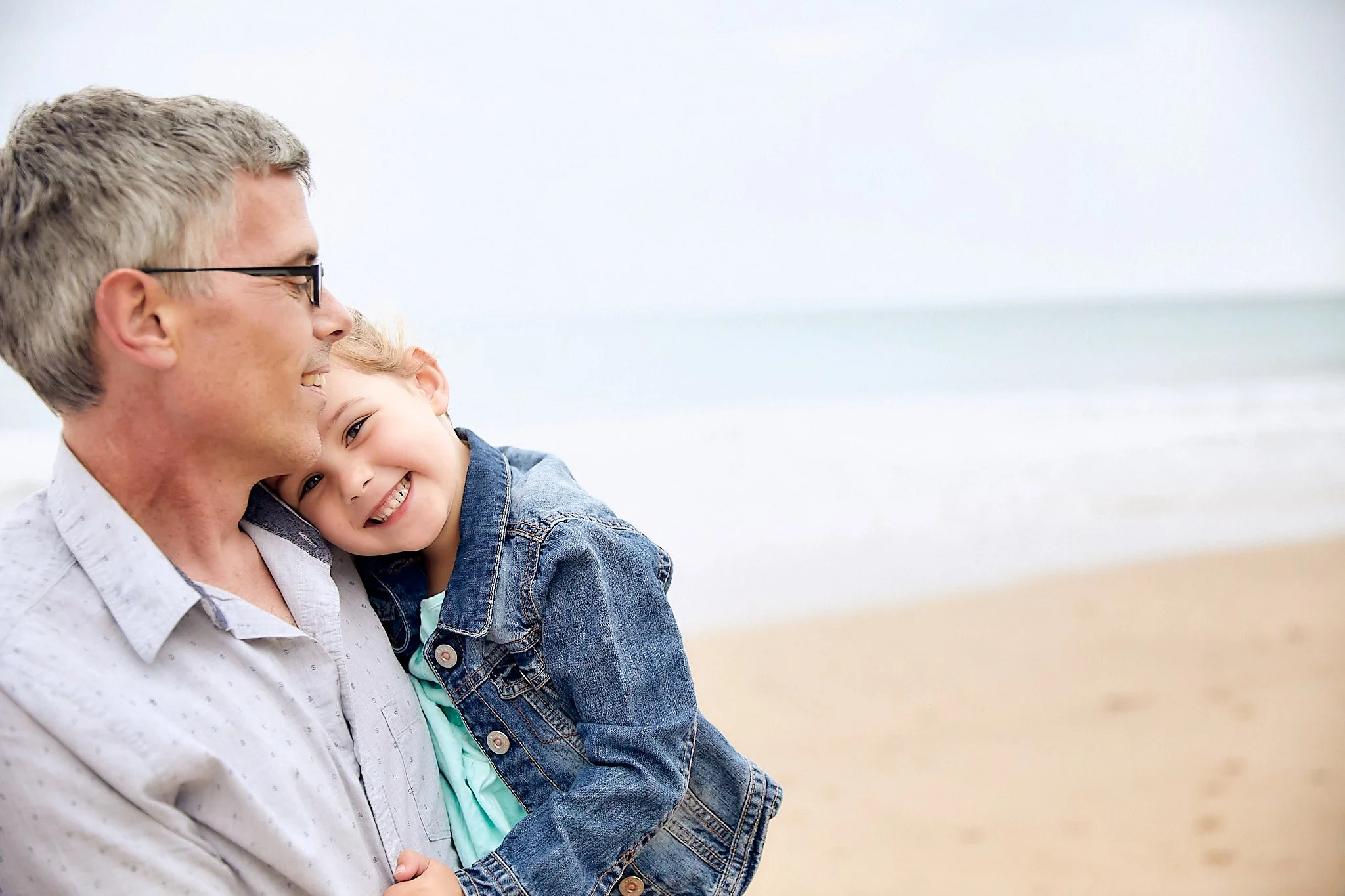 Man holding a smiling child at the beach
