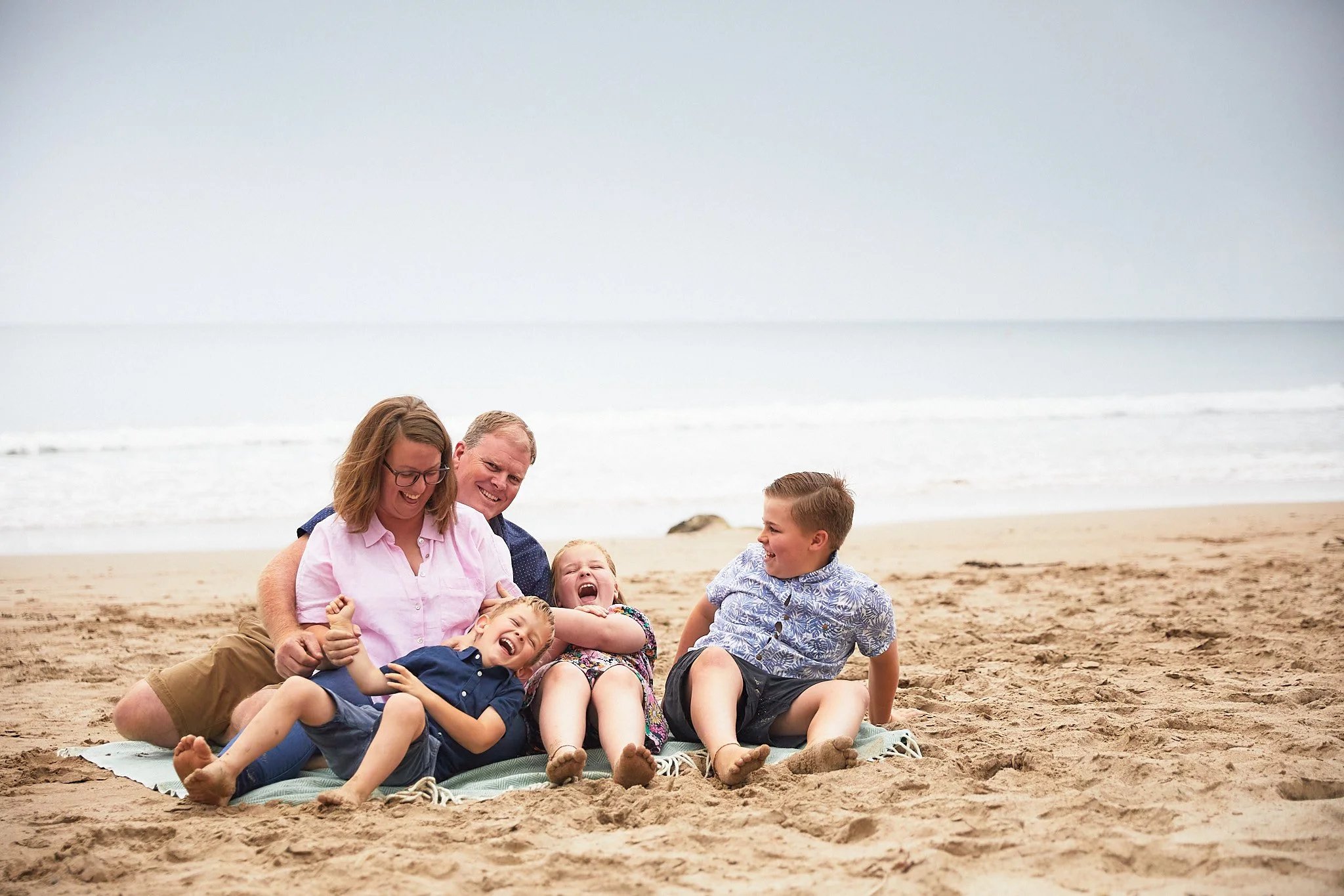 Family laughing together on a beach.