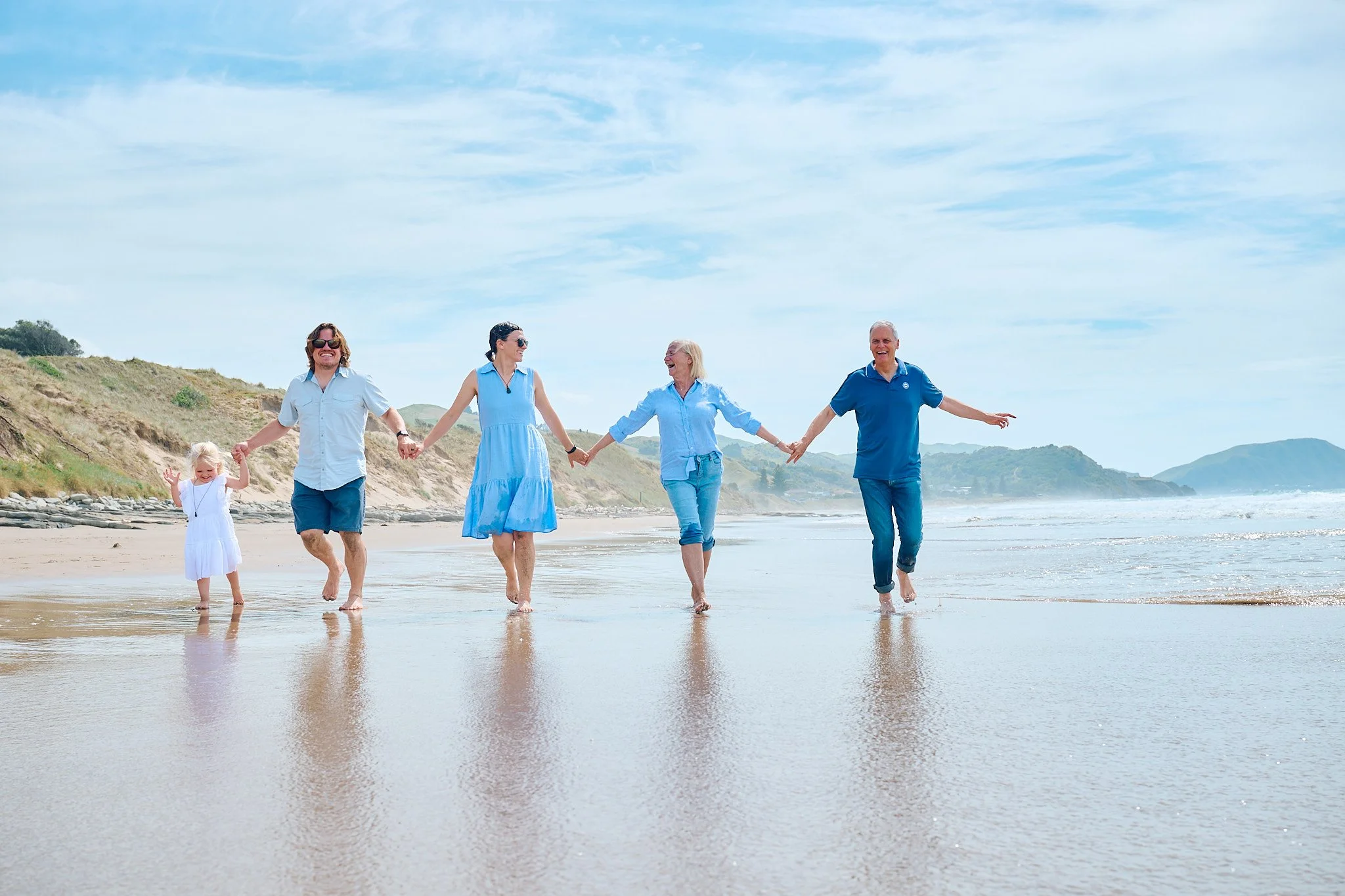 Family holding hands and walking on a beach