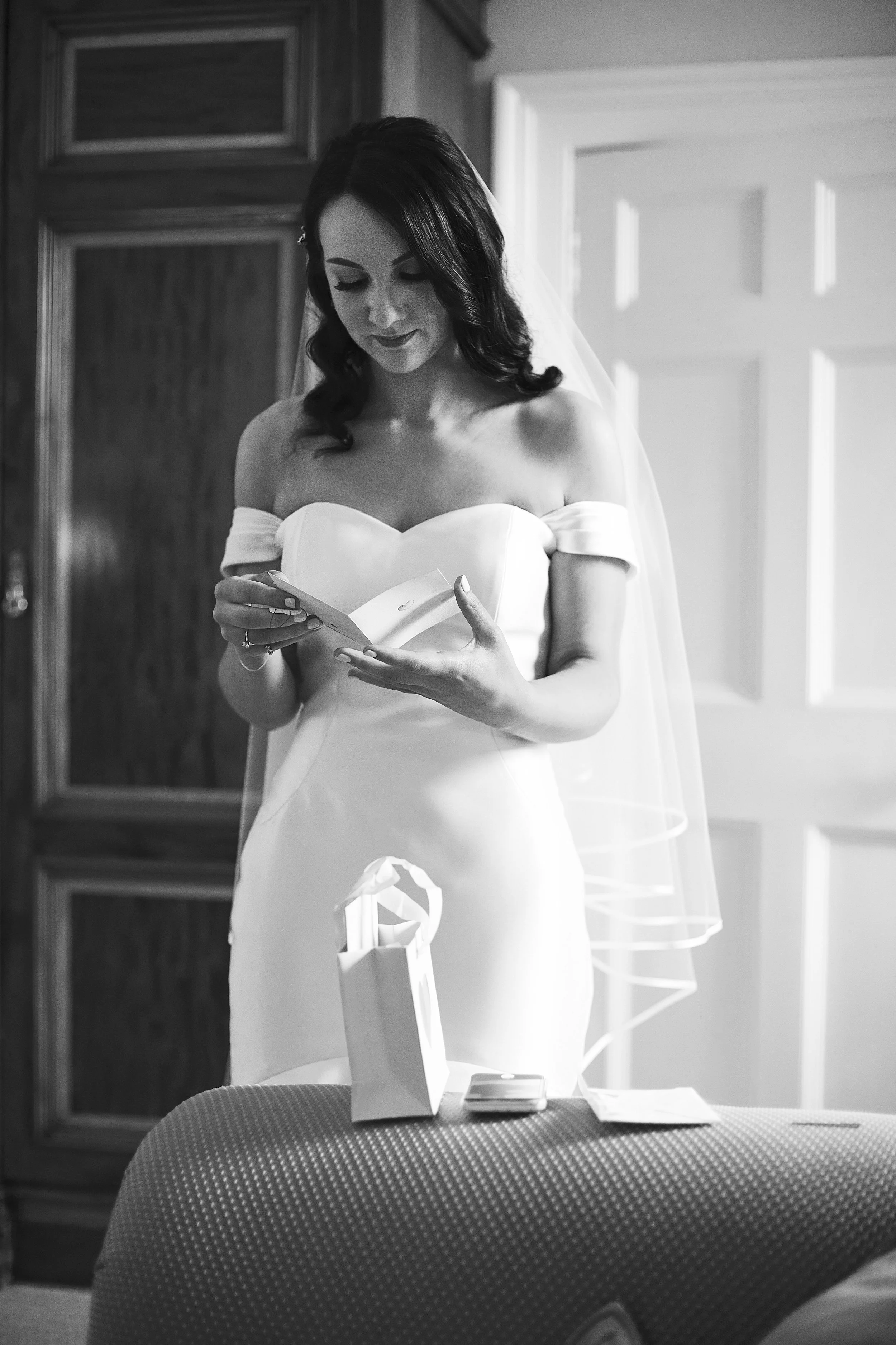 Bride in wedding dress reading a note indoors