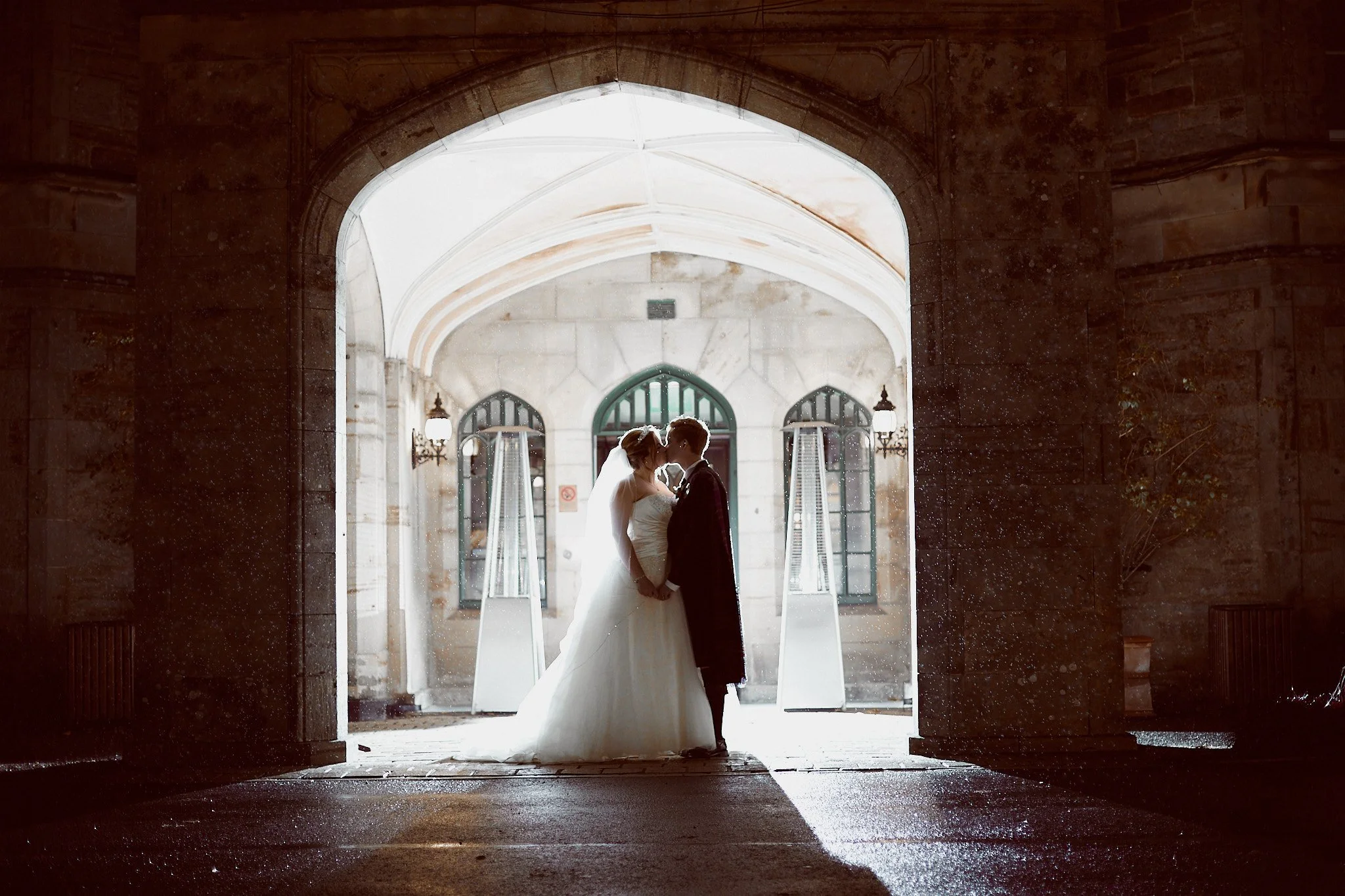 Bride and groom kissing in a stone archway