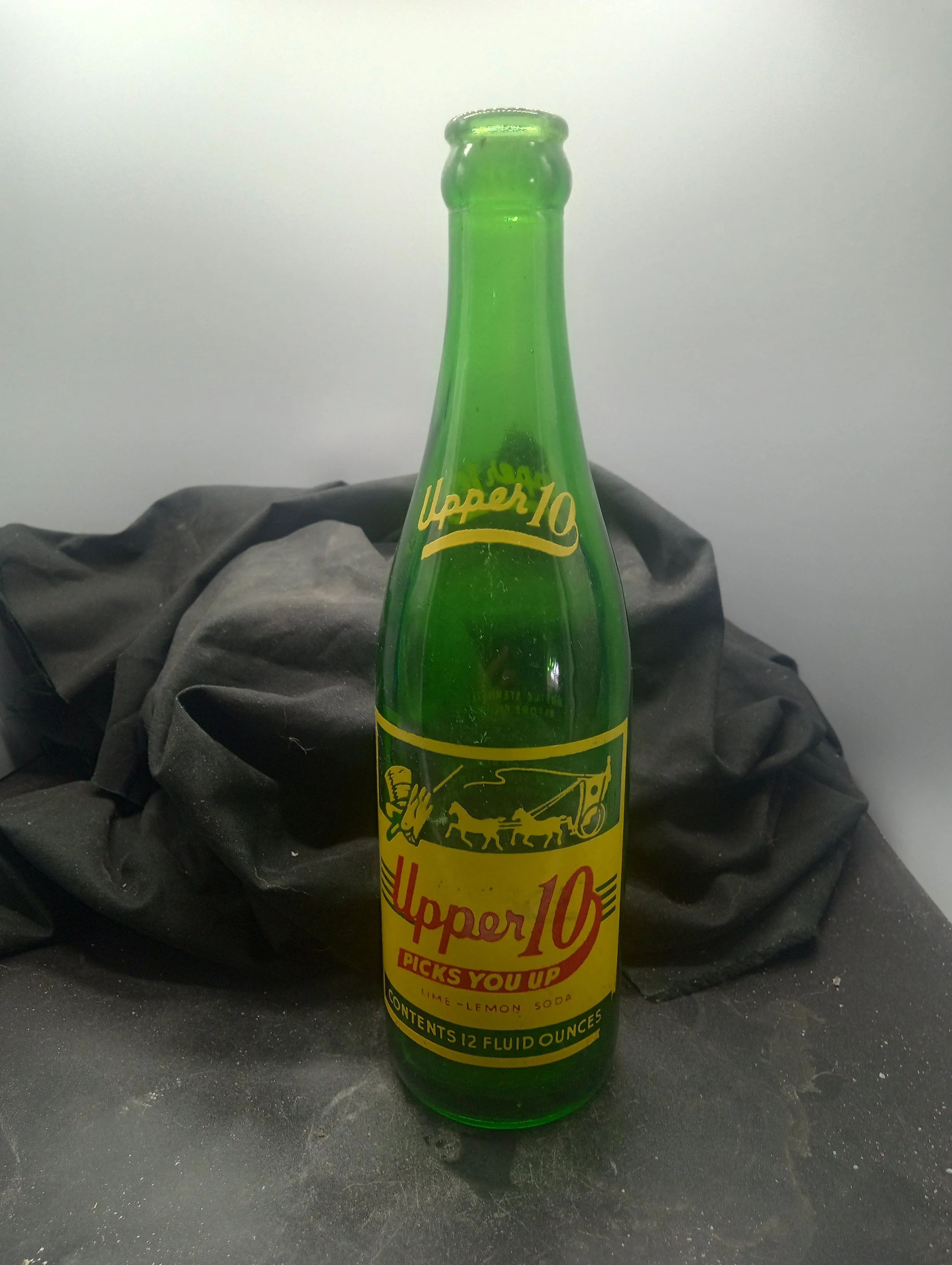AGE - 1952 - TYPE  - MACHINE - FRONT -  (shoulder) UPPER 10 (body) UPPER 10 / PICKS YOU UP / LIME - LEMON SODA / CONTENTS 12 FLUID OUNCES - BACK - PROPERTY OF / NEHI ROYAL CROWN BOTTLING CO. / SPARTANBURG, S.C. - COLOR - GREEN \ RARITY - COMMON