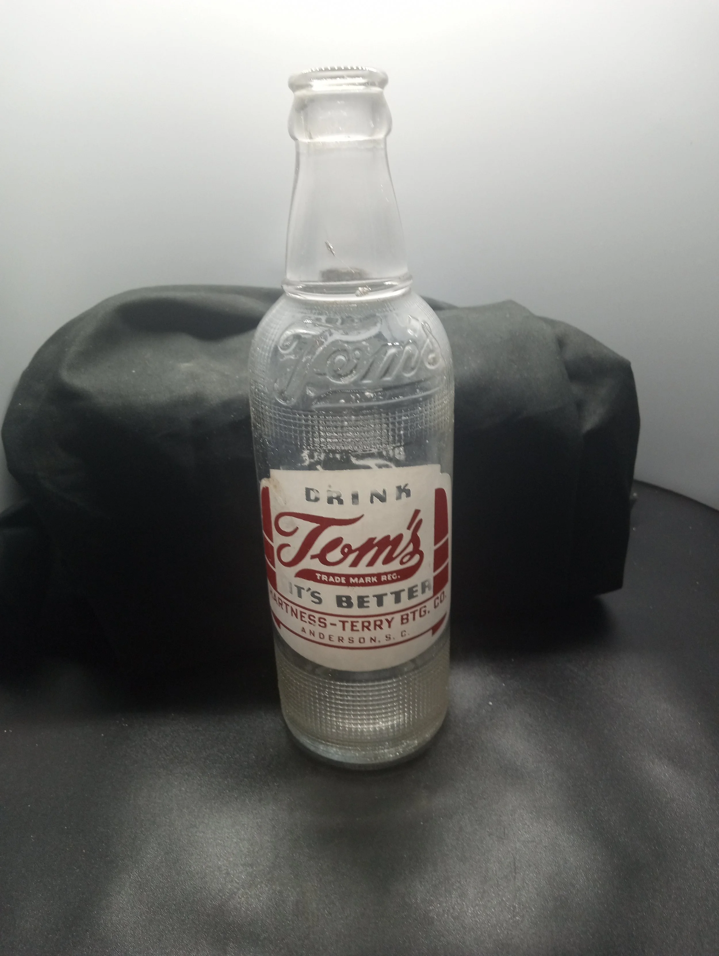 AGE- 1950 - TYPE - MACHINE - FRONT - (embossed at shoulder) TOM'S (body) DRINK / TOM'S / TRADE MARK REG. / IT'S BETTER / HARTNESS-TERRY BTG. CO. / ANDERSON, S.C. - BACK - CONTENTS 12 FLU. OZS. - BOTTOM - 5 L G W 0 1 541 - COLOR - CLEAR \ RARITY - S
