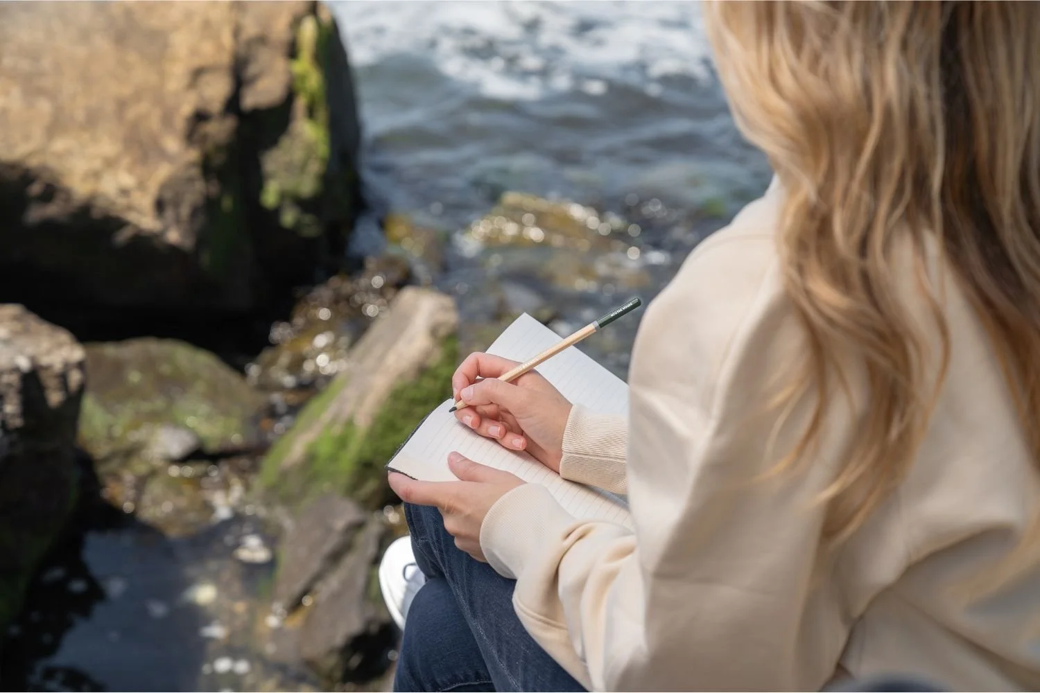 A woman writing about learned helplessness by the ocean.