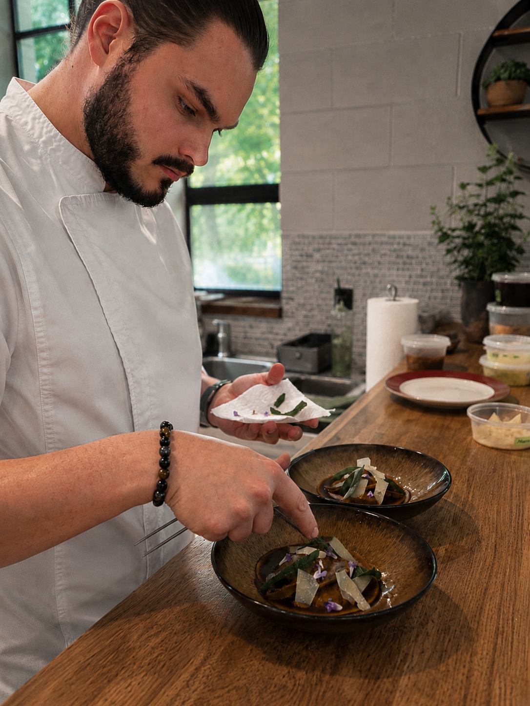 Chef Dylan Morgan, co-founder of Gourmet All Day, plating a dish in a client's kitchen