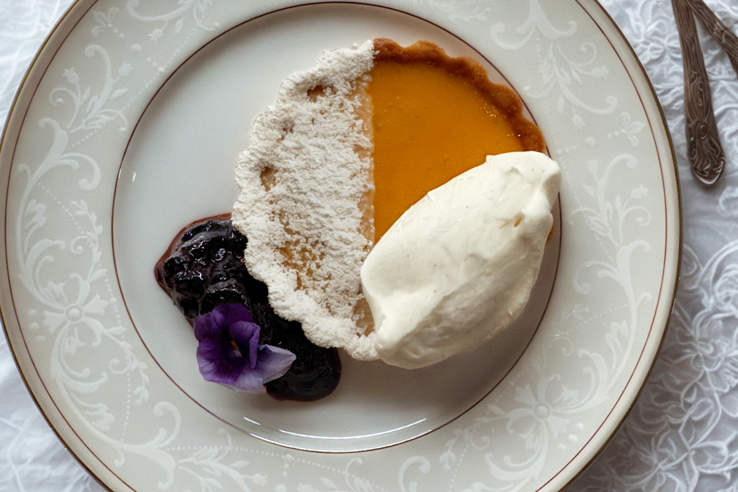 Plated mango tart dessert with whipped cream and blueberry compote