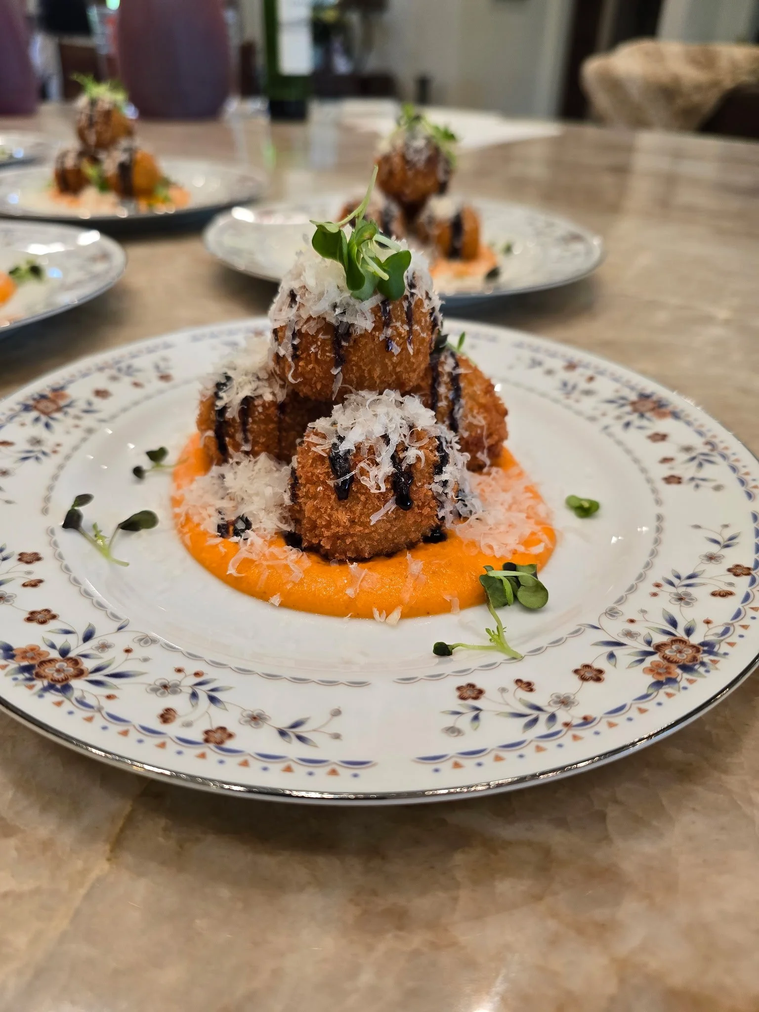 Crispy arancini appetizer with romesco, grated cheese, and microgreens