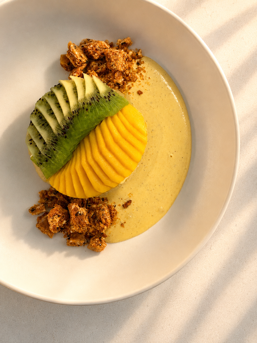 Plated dessert with fresh kiwi and mango with sabayon and sesame brittle