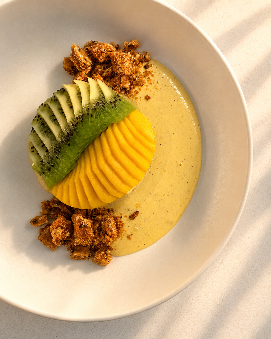 Plated dessert with fresh mango, kiwi, and sesame brittle