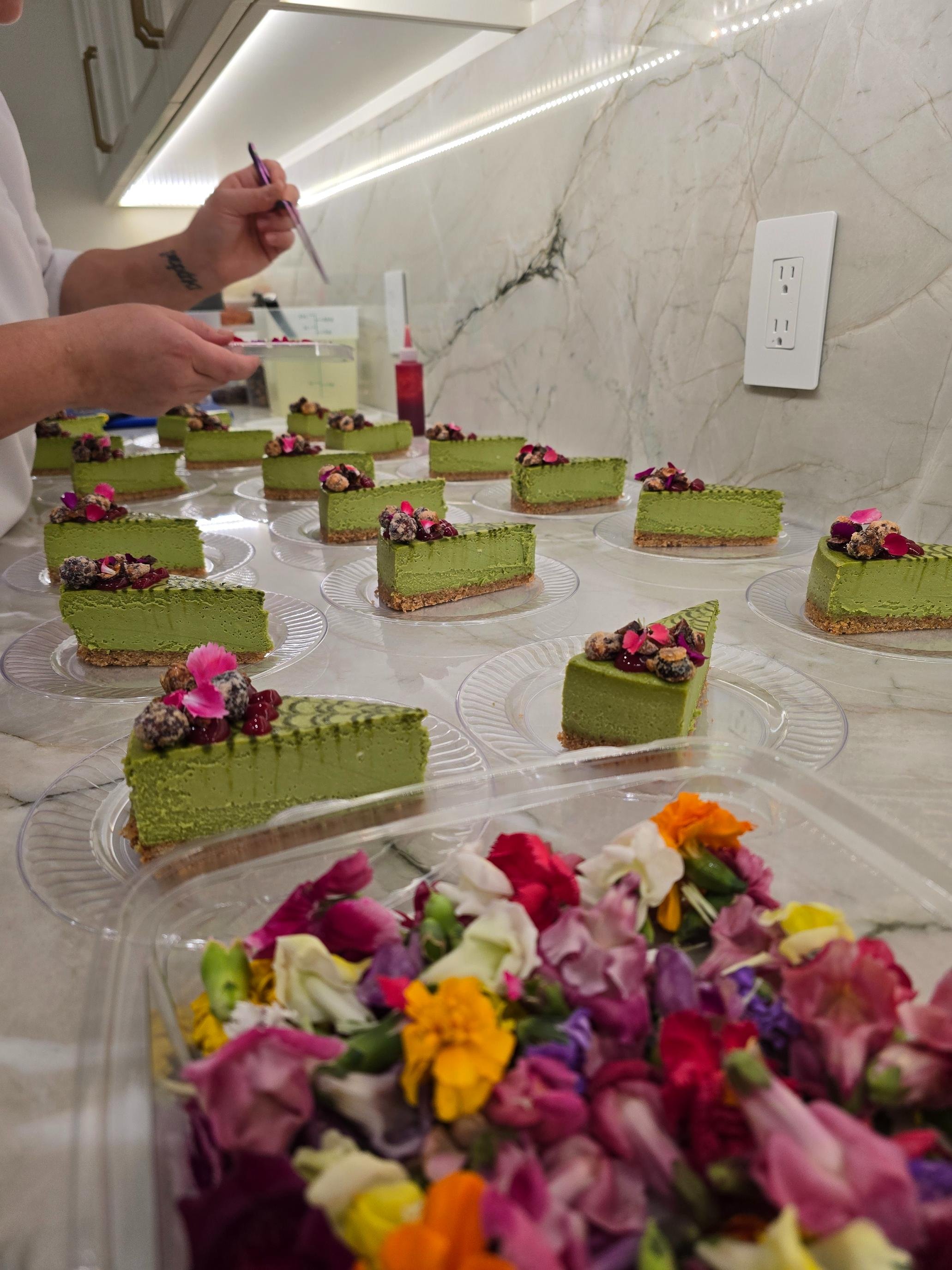 Individual matcha cheesecake slices being garnished with edible flowers