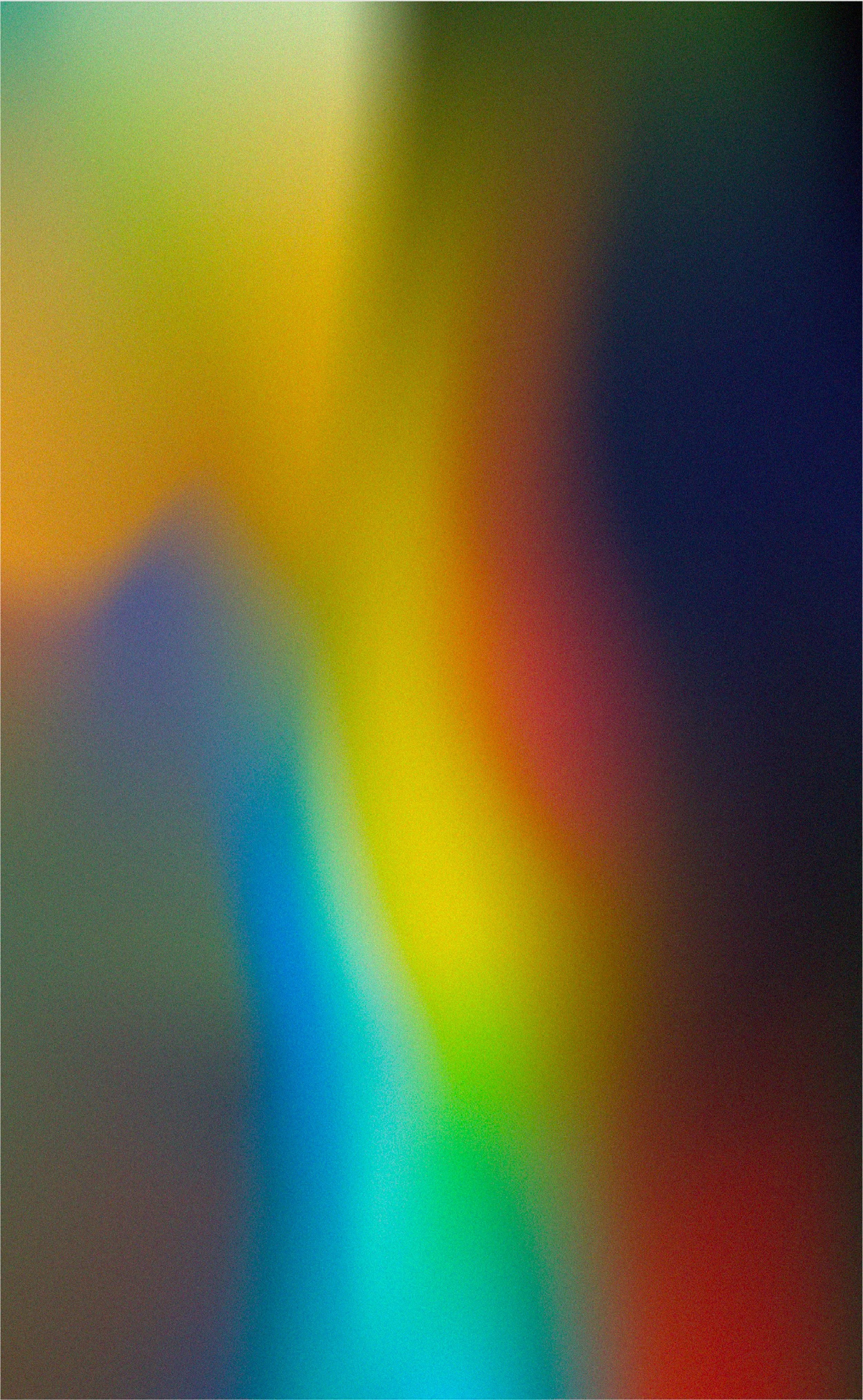 Blurred colorful abstract background with shades of yellow, green, blue, red, and black.
