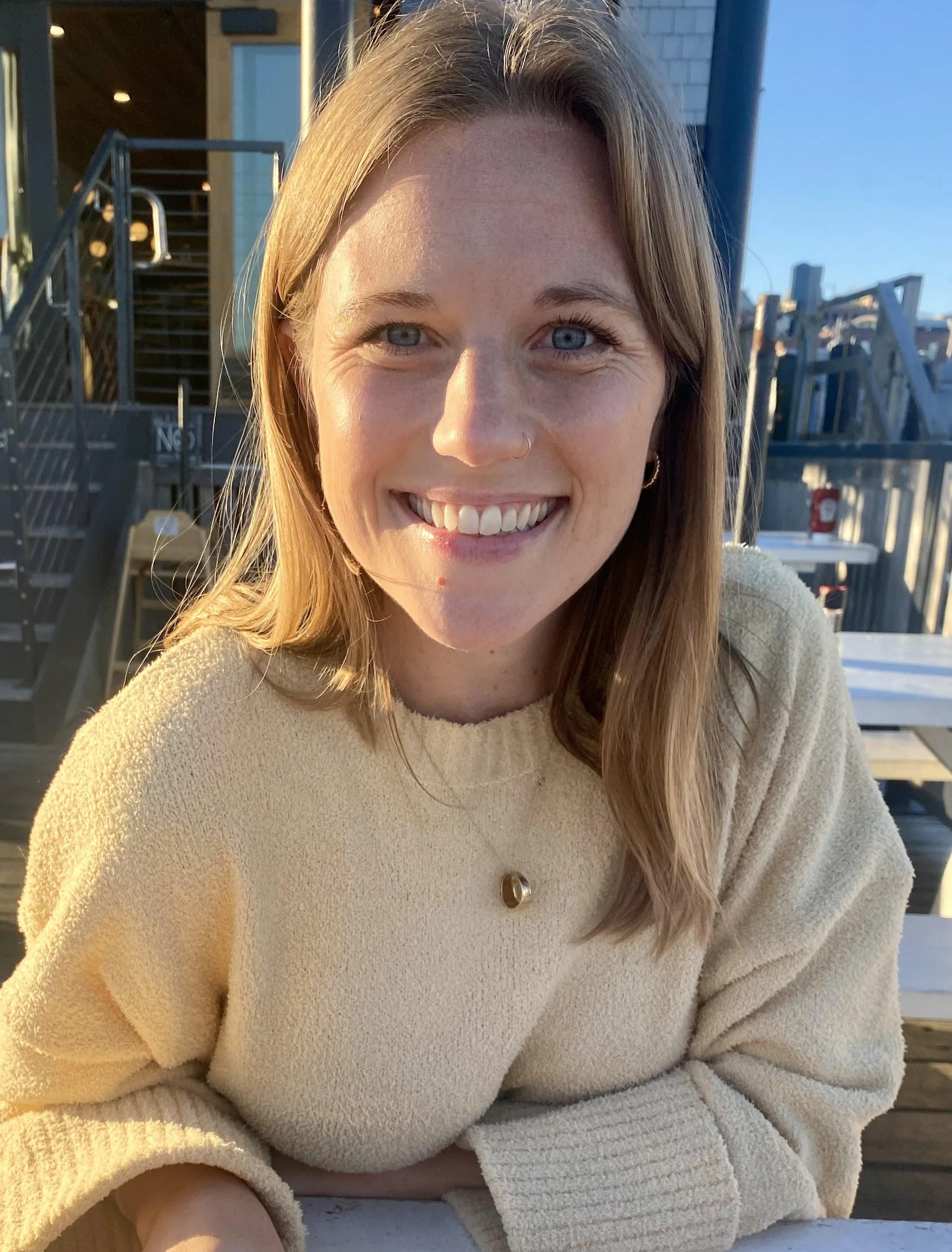Hannah Powell offering a warm smiling outdoors during the golden hour.