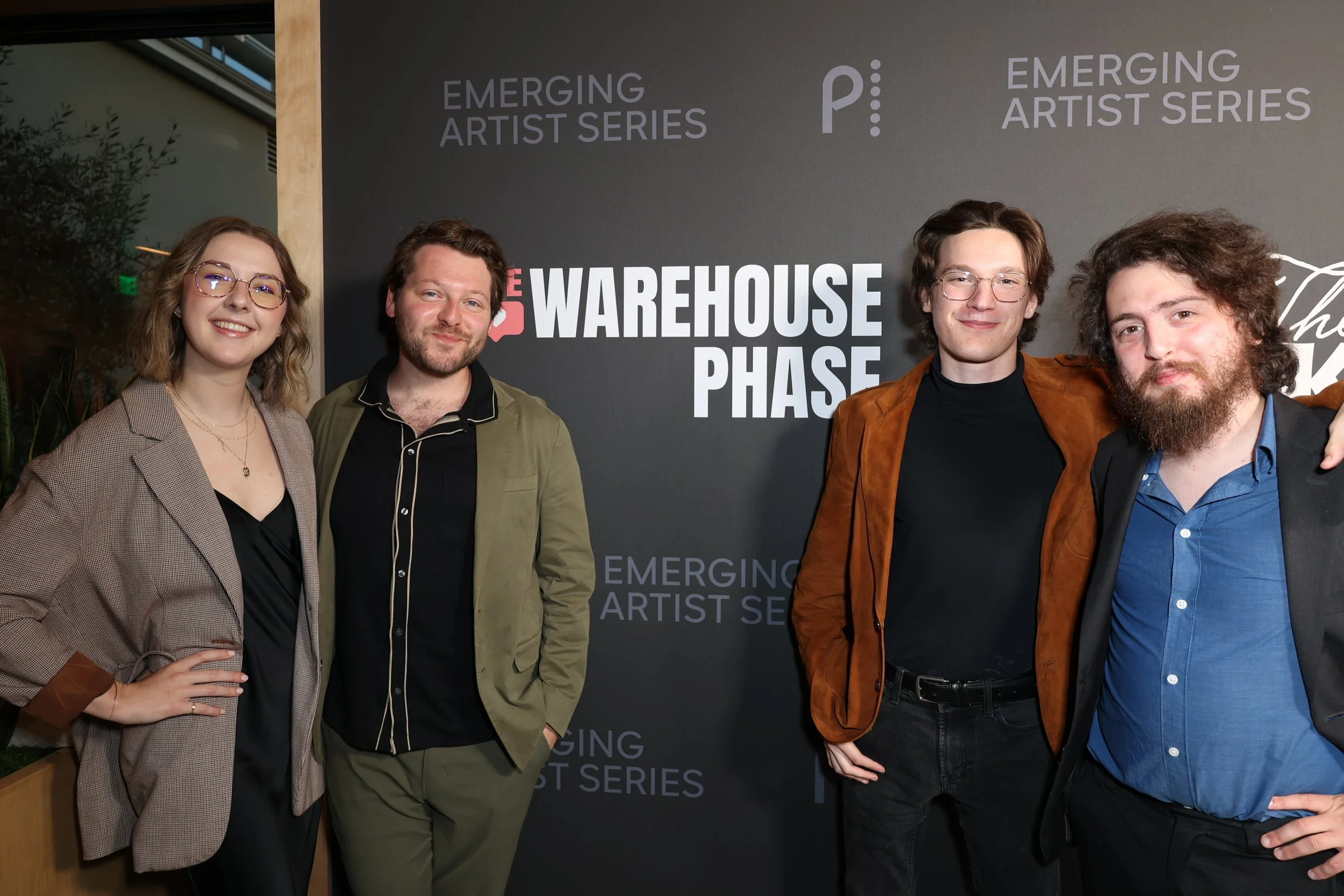 Four people standing together at an event with a backdrop that reads "Emerging Artist Series" and "Warehouse Phase". They are smiling and posing for the photo.