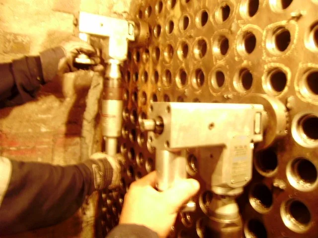 Persona trabajando reentubado de un intercambiador de calor.