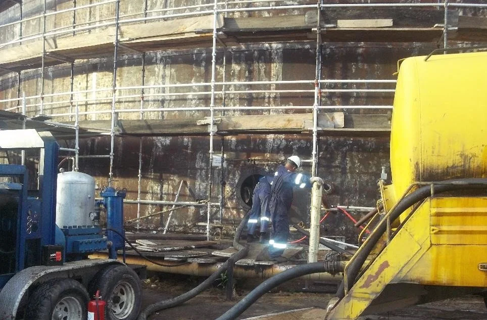 limpieza quimica, Trabajadores en una obra de construcción, con andamios alrededor de una estructura de concreto, usando equipo de protección y trabajando con maquinaria pesada