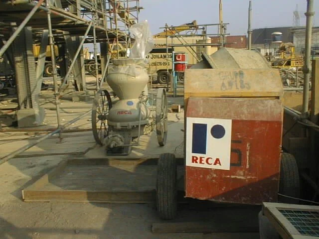 Equipo de construcción y maquinaria en un sitio de construcción con andamios y materiales de obra.