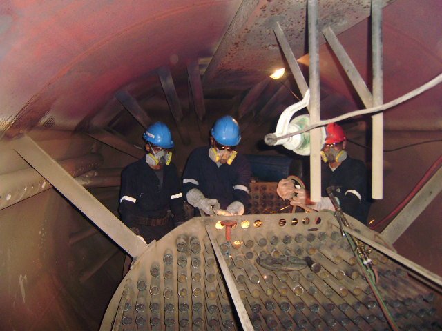 reentubado. Trabajador con equipo de protección utilizando una herramienta para intercambiador de calor .