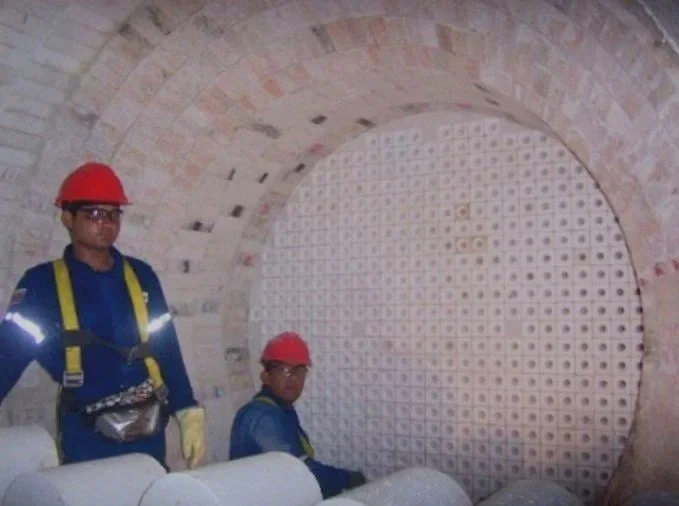 Hormo Clauss.trabajadores con cascos rojos trabajando en la construcción de un horno, observando .