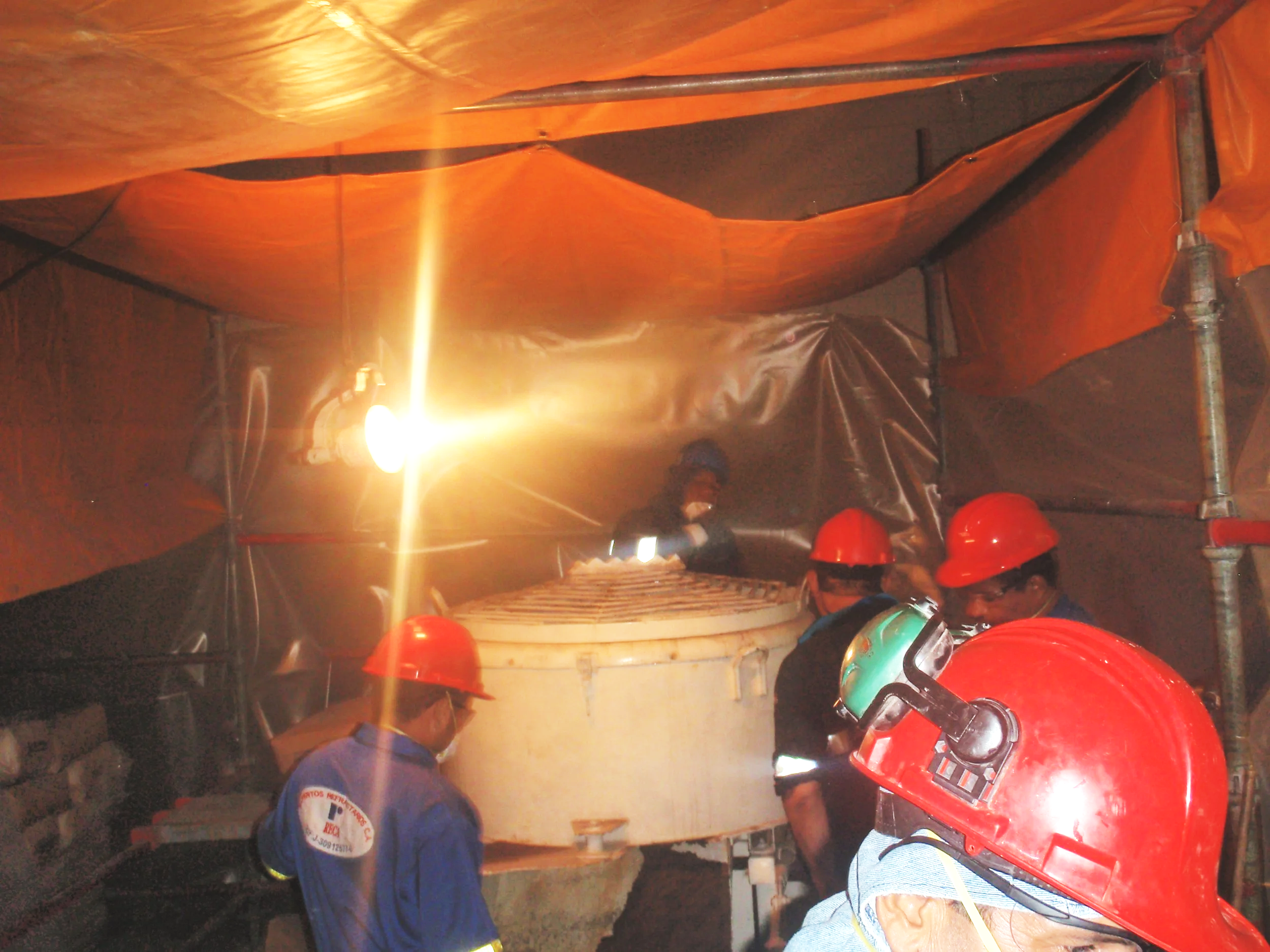 Personal en la mezcladora en  sitio de construcción observando una estructura con equipo de protección.