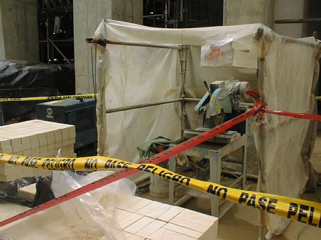 Una zona de trabajo con cinta de advertencia, una mesa cortadora de ladrillo