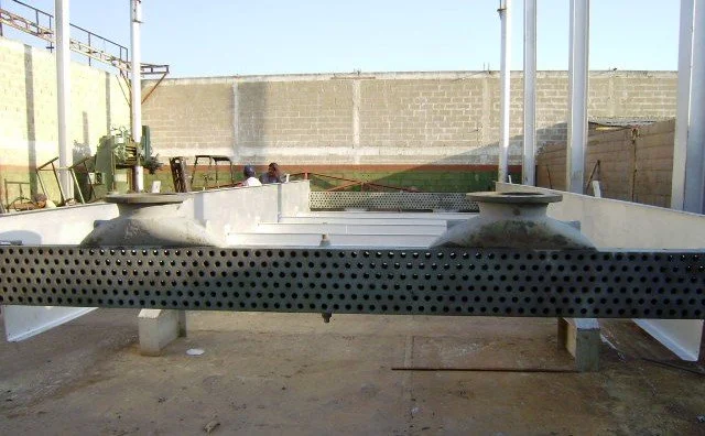 Intercambiadores de calor, Vigas de metal de color plata apoyadas sobre caballetes de madera en un taller.