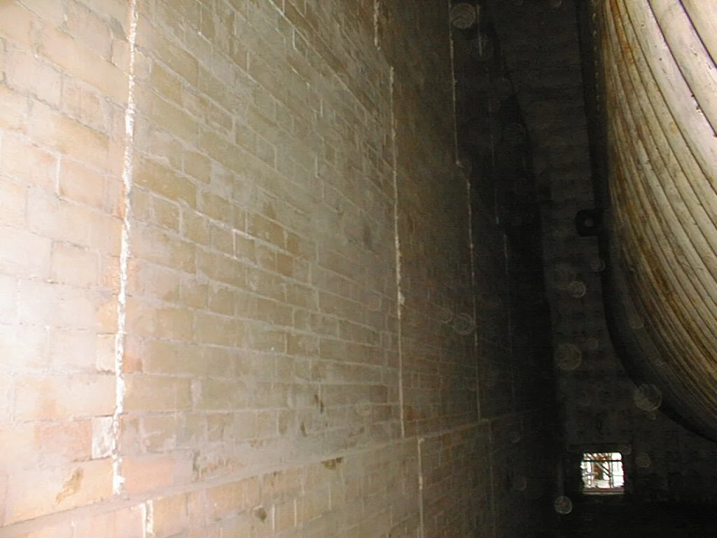 Pared de ladrillos en una pared interior, con una ventana pequeña en el fondo.