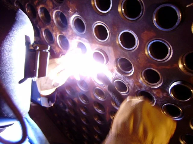 reentubado. Trabajador con equipo de protección utilizando una herramienta para intercambiador de calor .