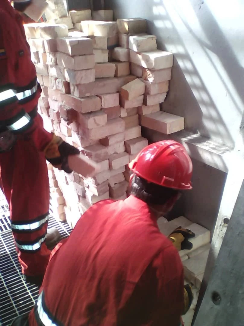 	
interior horno Trabajadores con cascos y ropa de seguridad manipulando ladrillos en construcción.