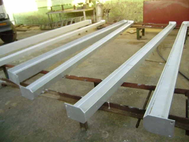 Vigas de metal de color plata apoyadas sobre caballetes de madera en un taller 