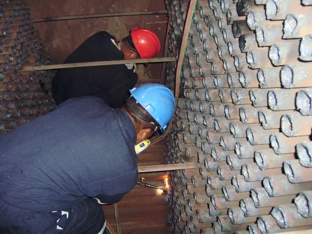 reentubado. Trabajador con equipo de protección utilizando una herramienta para intercambiador de calor .