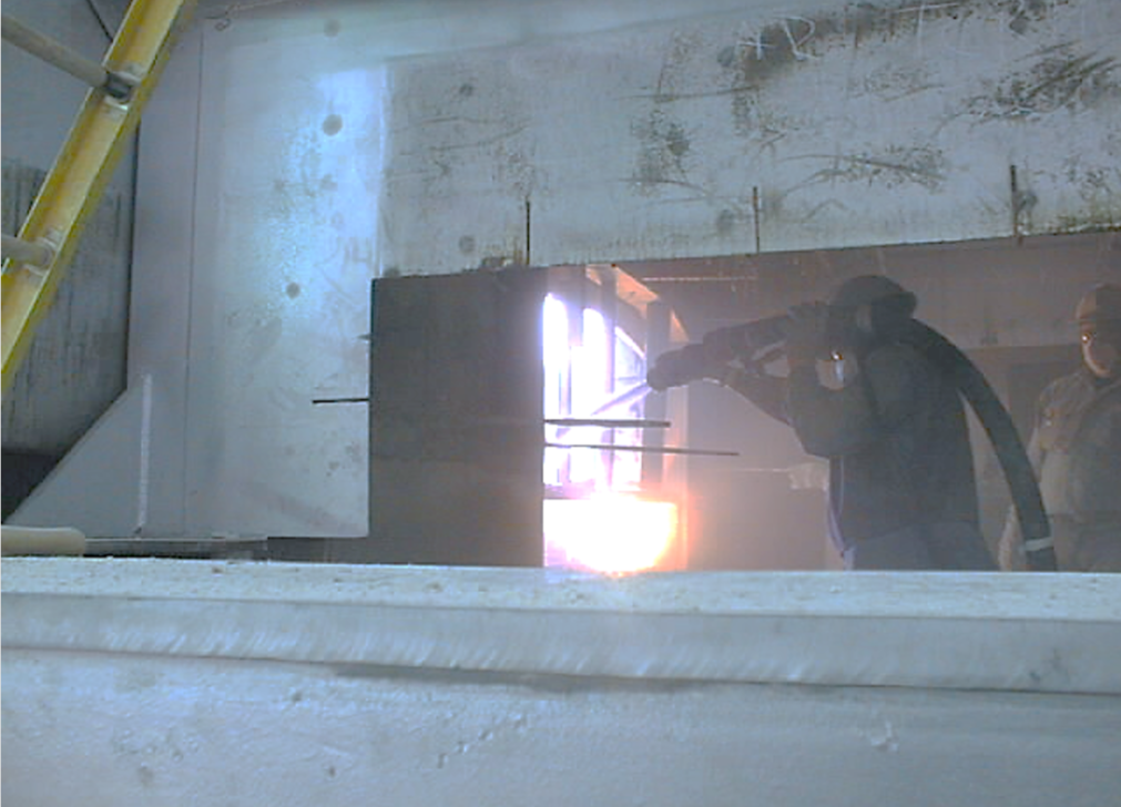 Trabajador proyectando  material refractario una horno  industrial.