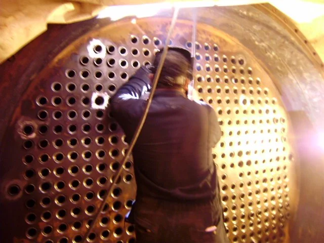 reentubado. Trabajador con equipo de protección utilizando una herramienta para intercambiador de calor .