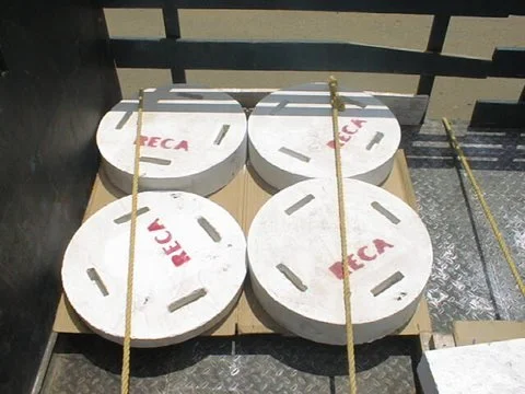 Cuatro piezas especiales material refractario  en una caja de madera, con marcas rojas y bandas de cuerda amarilla en cada uno.