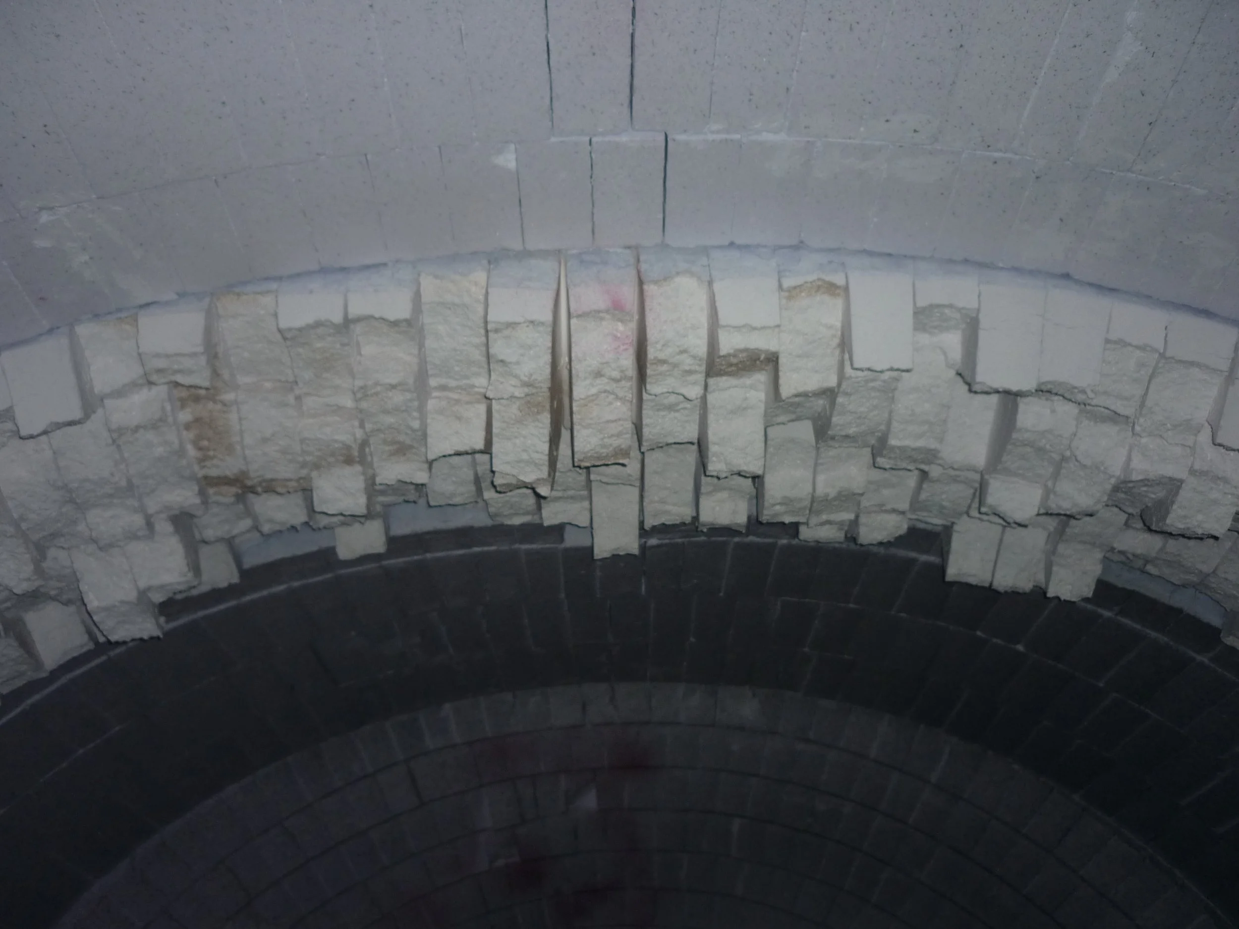 Horno clauss. Vista de una cúpula de ladrillos y piedras en construcción o restauración, con piedras blancas en el centro y ladrillos oscuros en la parte inferior.
