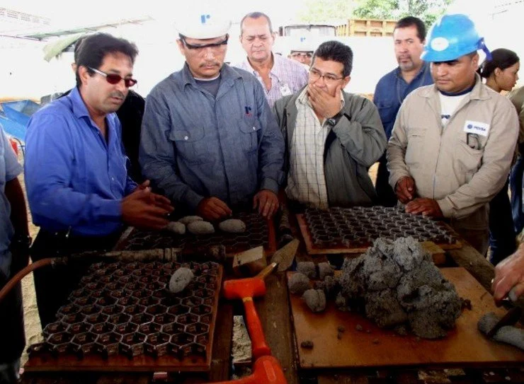 Hombre mostrando un material a un grupo de personas en lo que parece ser una demostración material refractario