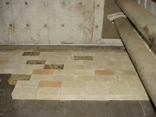 personas trabajando en un horno colocando ladrillos en el suelo.