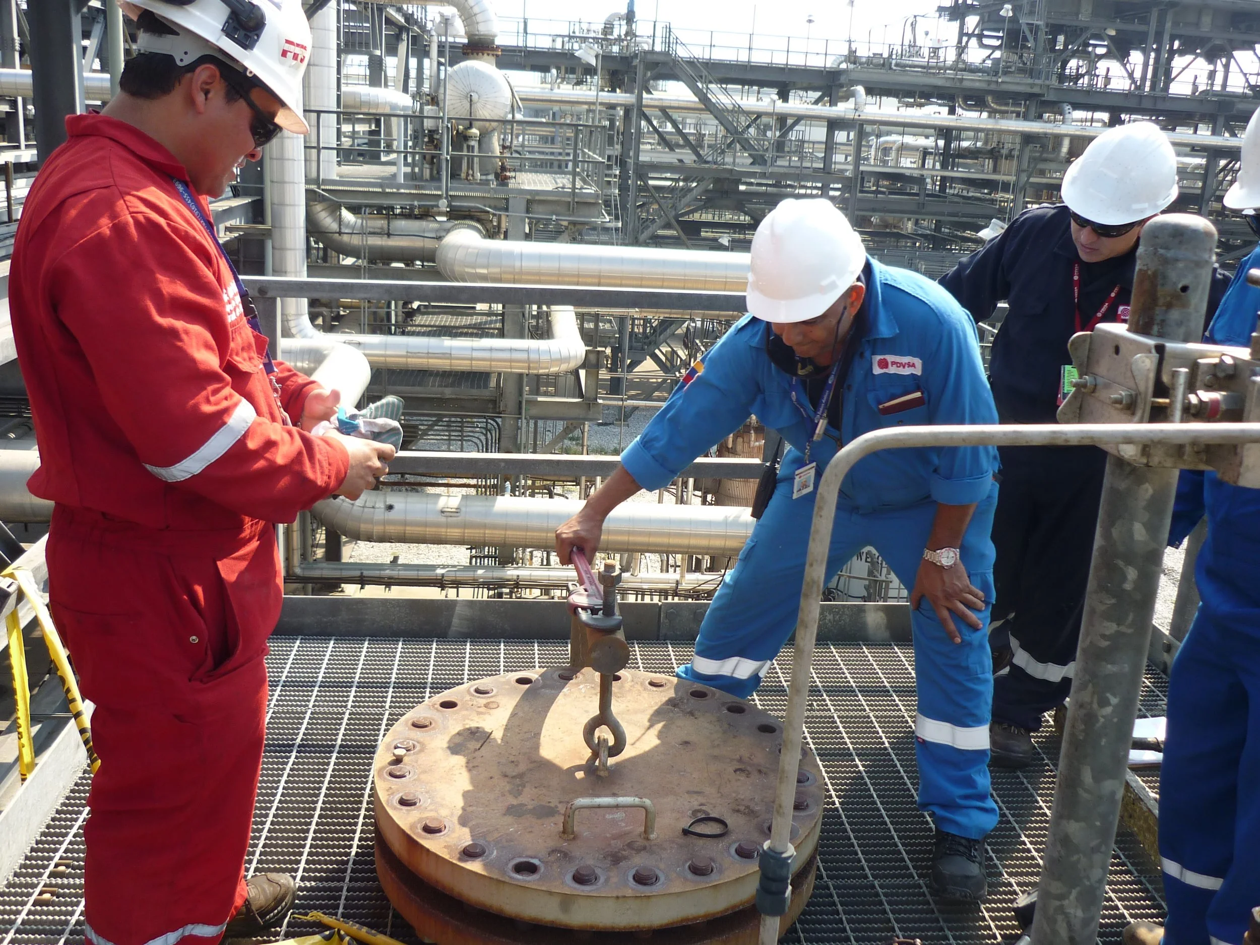 Trabajadores en un entorno industrial, haciendo mantenimiento en una estructura metálica y postes de tuberías.