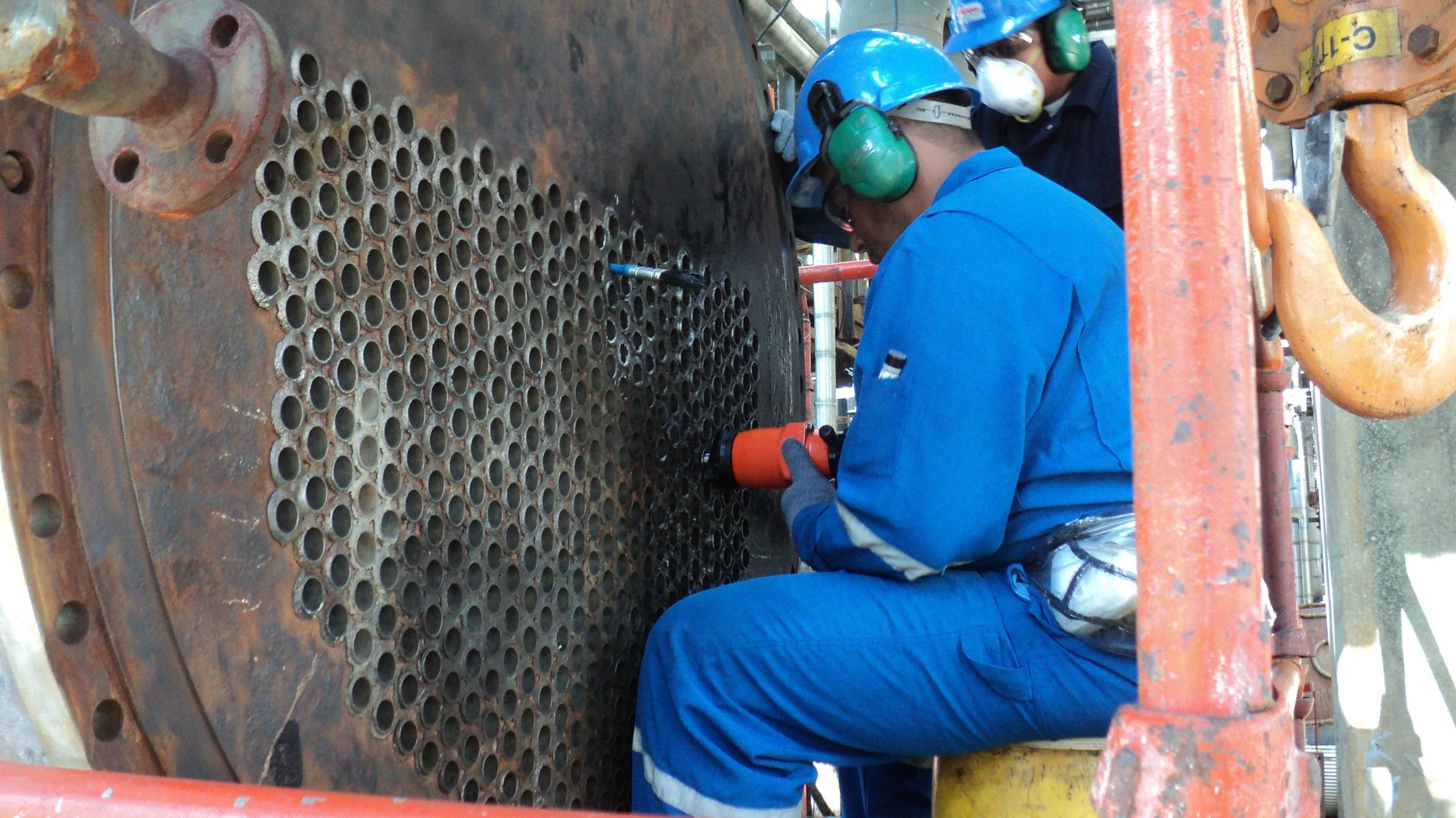 reentubado. Trabajador con equipo de protección utilizando una herramienta para intercambiador de calor .