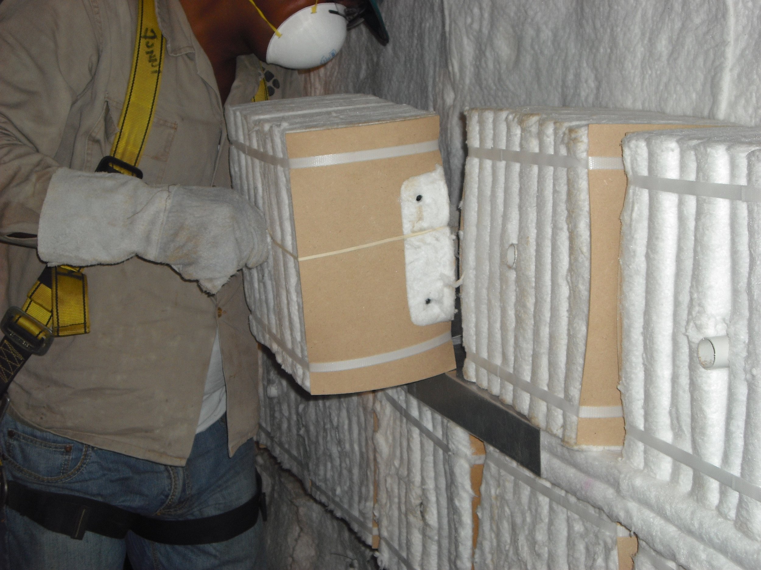 Persona con equipo de proteccióninstalando fibra ceramica en una pared de herno.