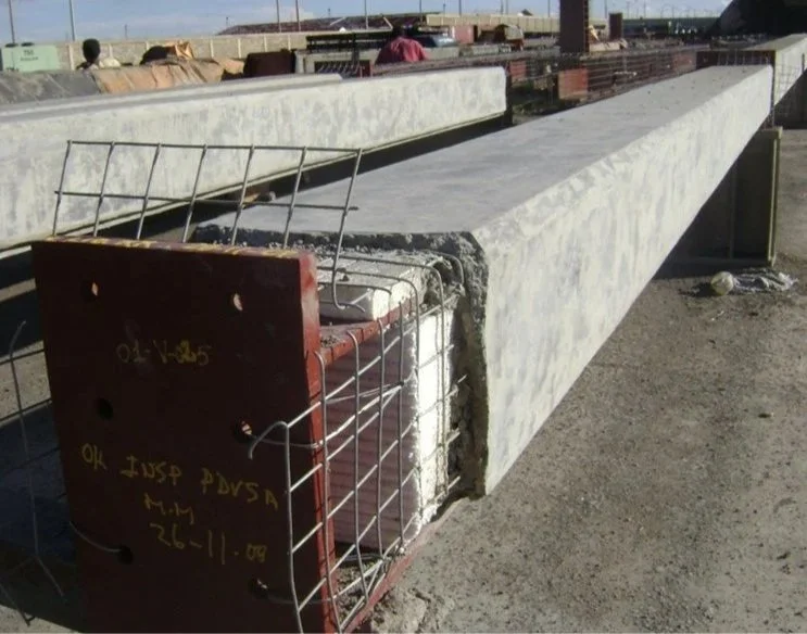 Viga de concreto en construcción con protección metálica en un sitio de obras.