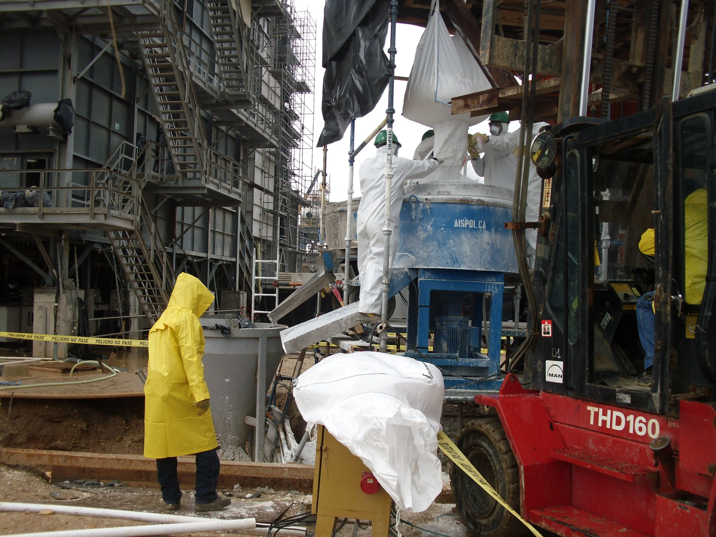 vaciado de reformador secundario. Trabajadores en sitio de construcción usando equipo de protección, manipulando maquinaria y materiales de construcción en un entorno de obra.